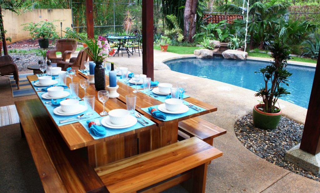 The teak table set for dinner with the pool behind at Casa Colorado, a vacation rental home with a private pool in Tamarindo, Costa Rica