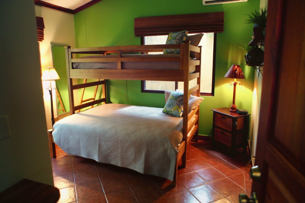 The bunk room with green walls and air conditioning at Casa Colorado, a vacation rental home with a private pool in Tamarindo, Costa Rica