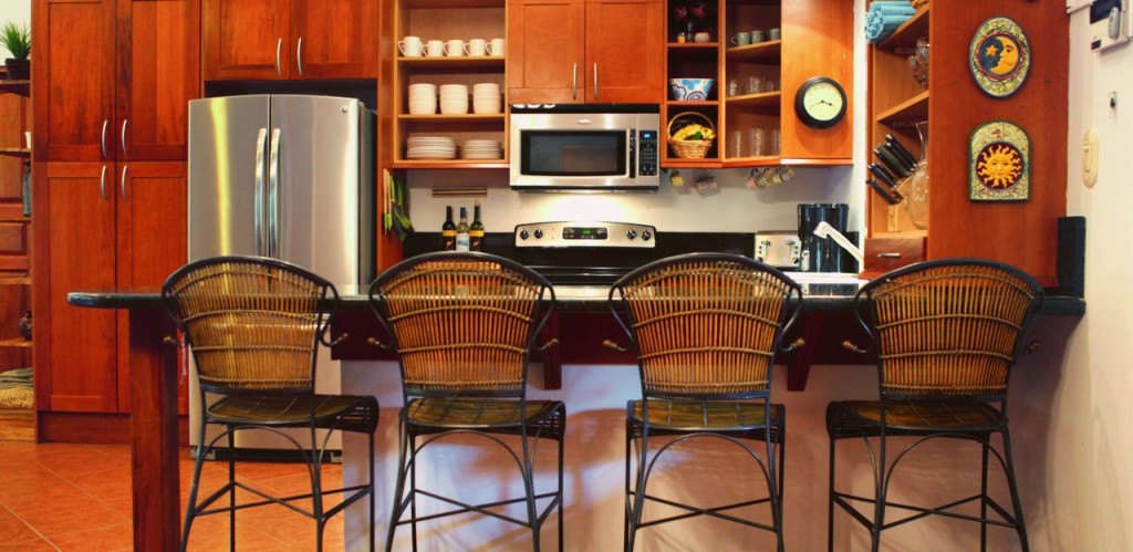 The kitchen island with bar stools and stainless appliances at Casa Colorado, a vacation rental home with a private pool in Tamarindo, Costa Rica