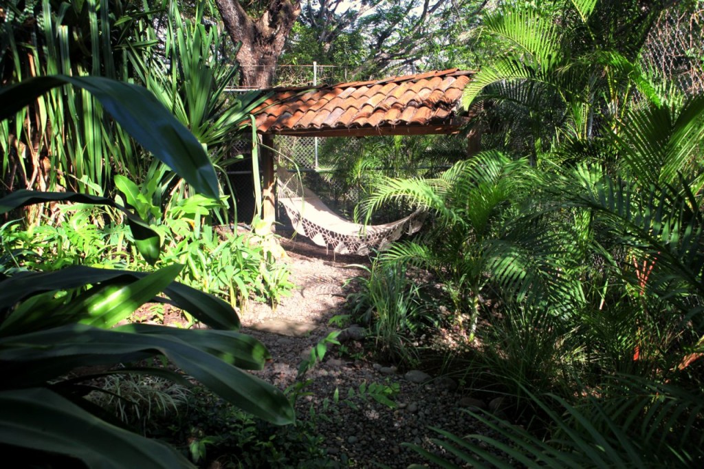 A hammock under the eaves in the jungle garden at Casa Colorado, a vacation rental home with a private pool in Tamarindo, Costa Rica