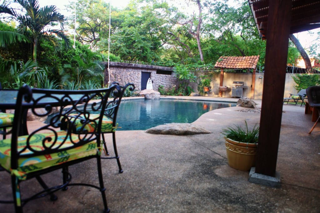 Iron chairs on the pool deck in the shade at Casa Colorado, a vacation rental home with a private pool in Tamarindo, Costa Rica