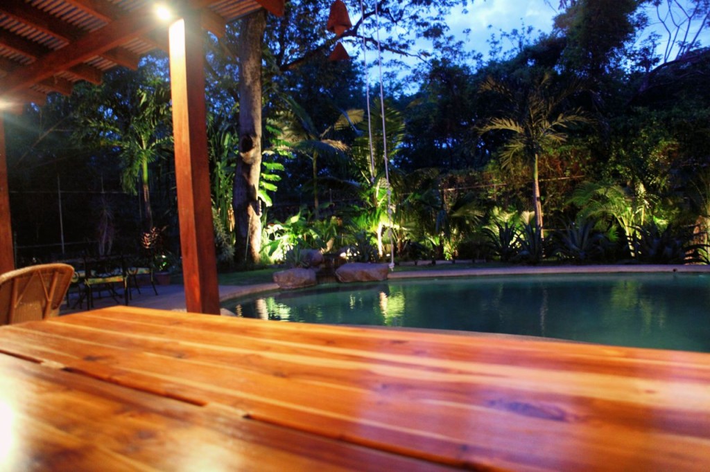 Looking across the teak table to the pool at night at Casa Colorado, a vacation rental home with a private pool in Tamarindo, Costa Rica