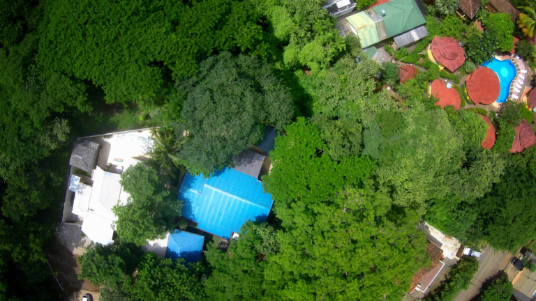 Overhead drone view of Casa Colorado surrounded by dense green jungle canopy in Tamarindo, Costa Rica
