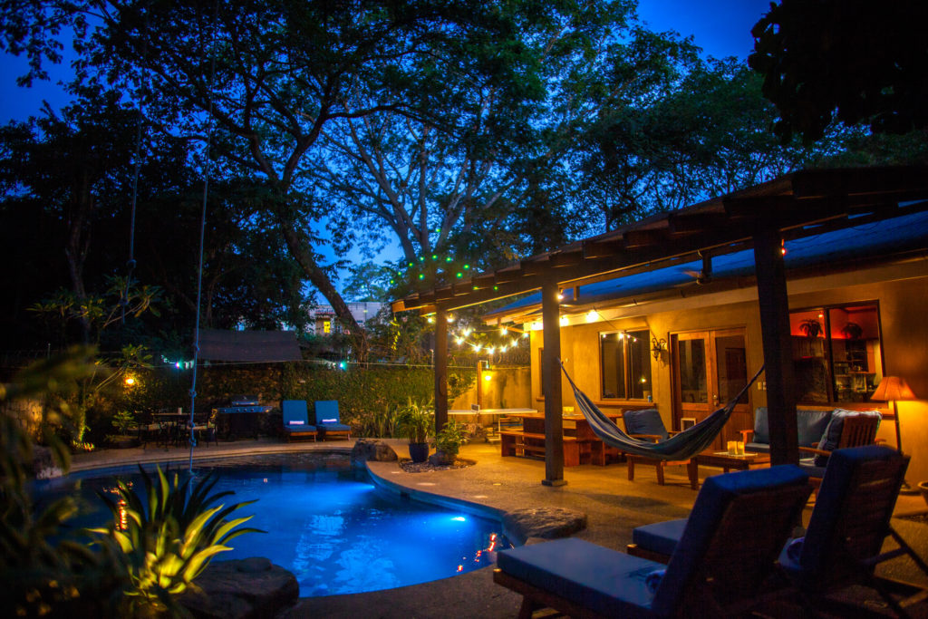 The main house and patio seen across the pool at dusk at Casa Colorado, a vacation rental home with a private pool in Tamarindo, Costa Rica