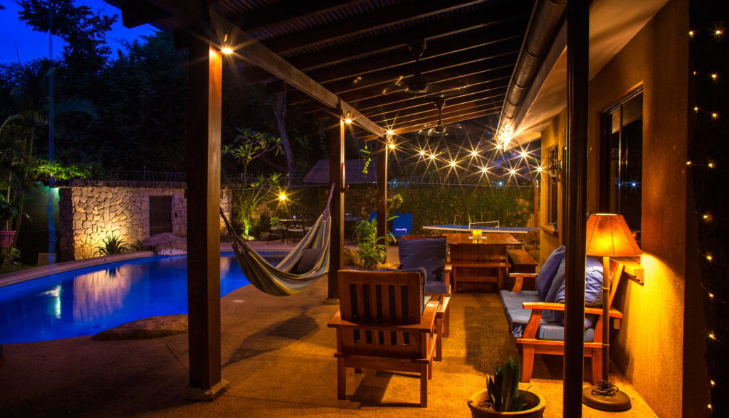 The covered patio at night under café lights, with a hammock at Casa Colorado, a vacation rental home with a private pool in Tamarindo, Costa Rica